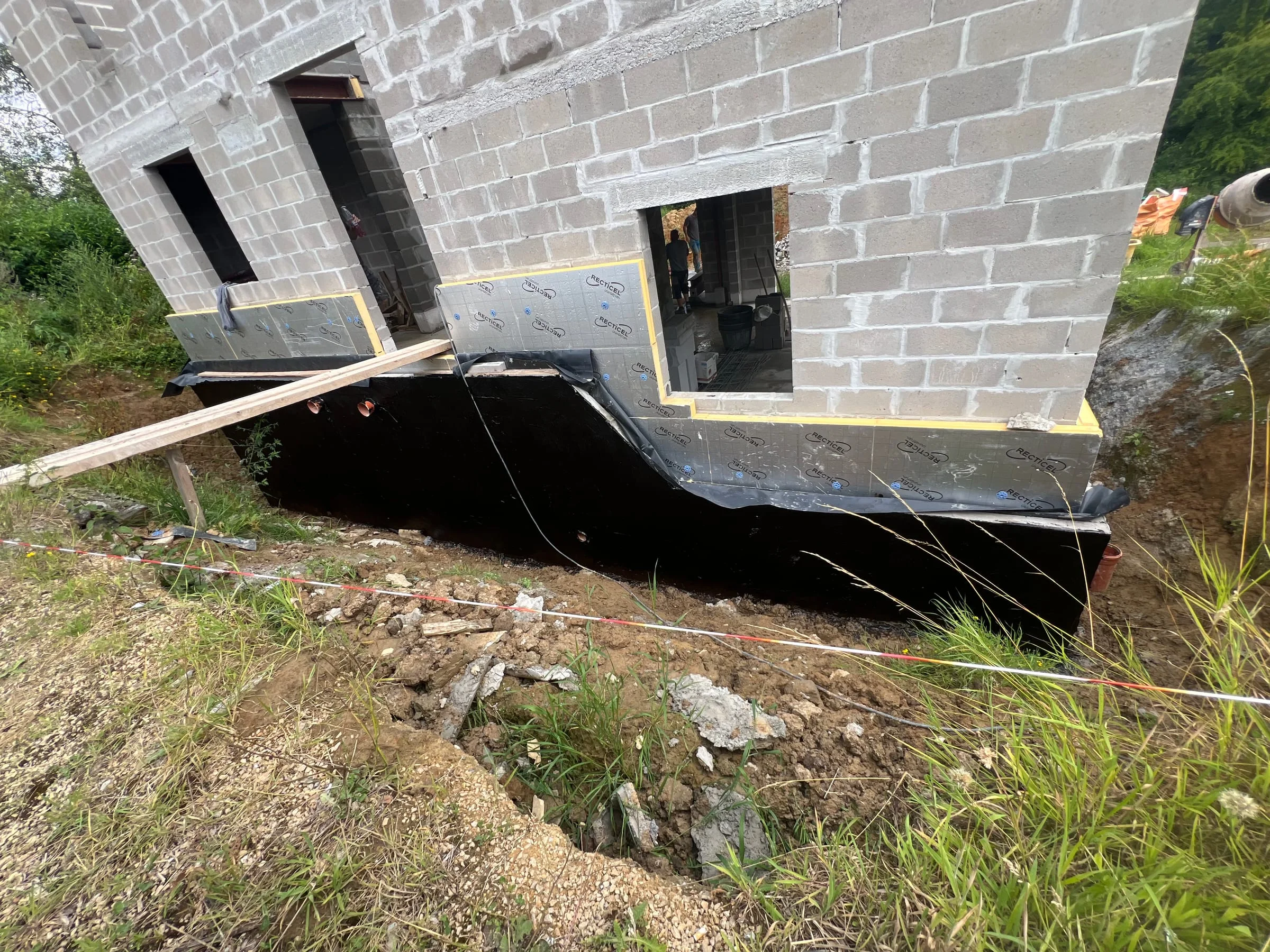 Étanchéité noire appliquée au pied d’un mur de soubassement