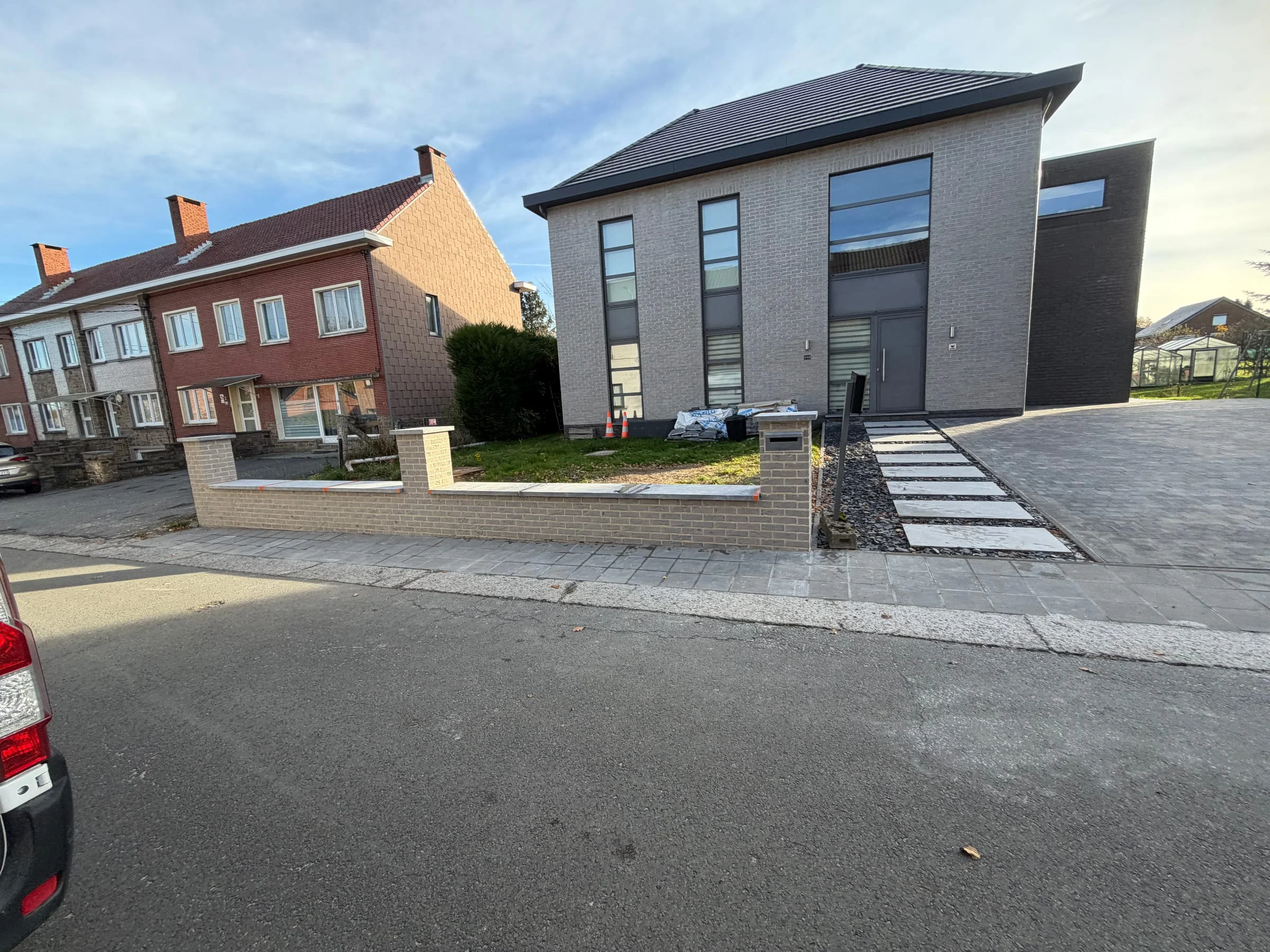 Façade avant avec parking pavé et murets en briques terminés