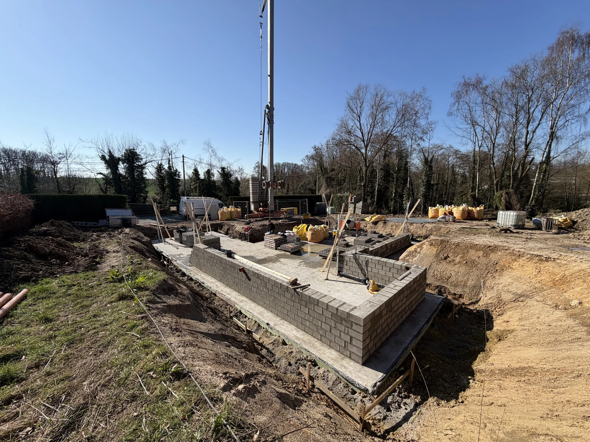 Premiers murs de fondation en blocs avec la grue du chantier