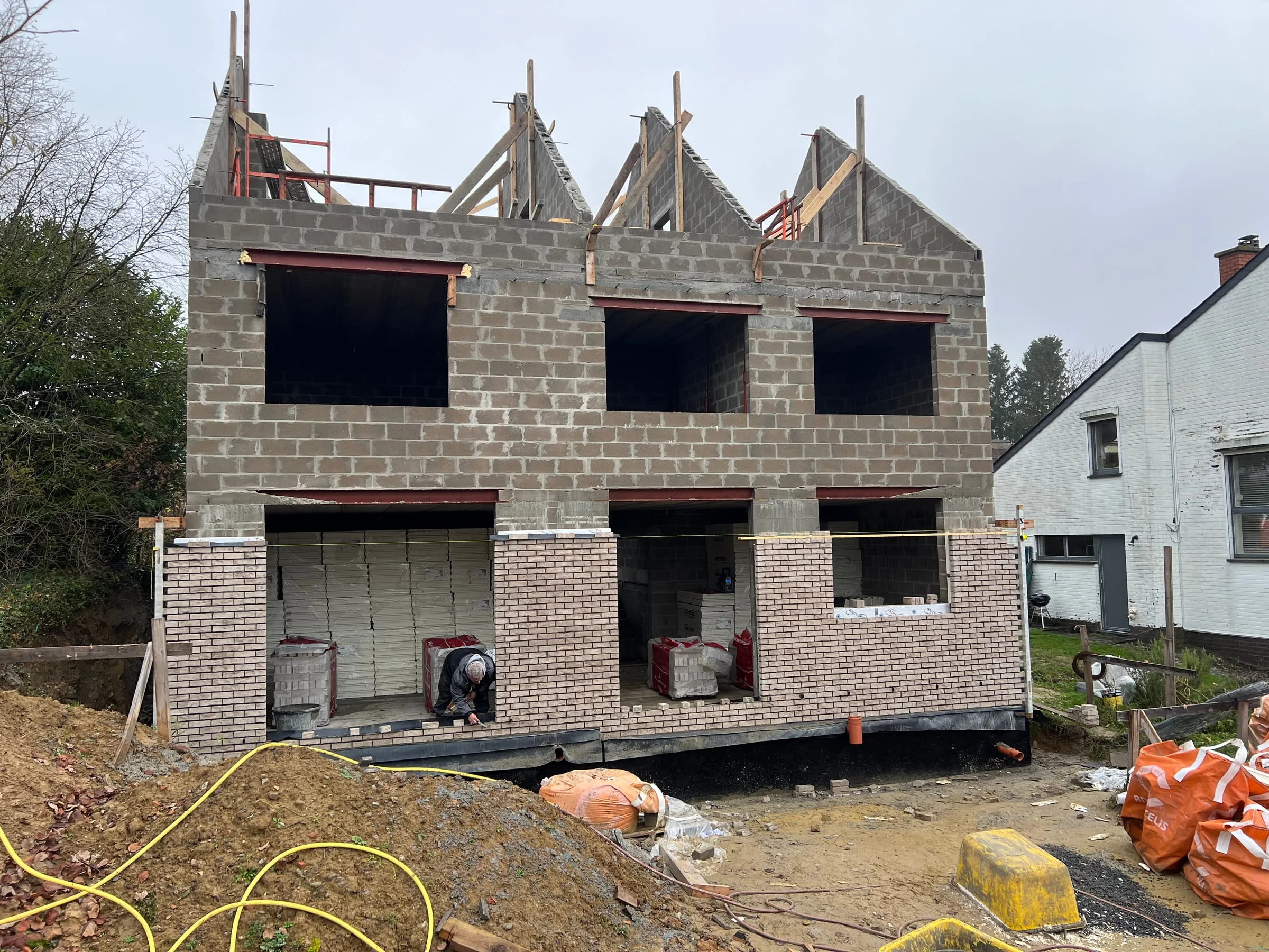 Façade avant en construction avec murs en blocs et charpente de toiture