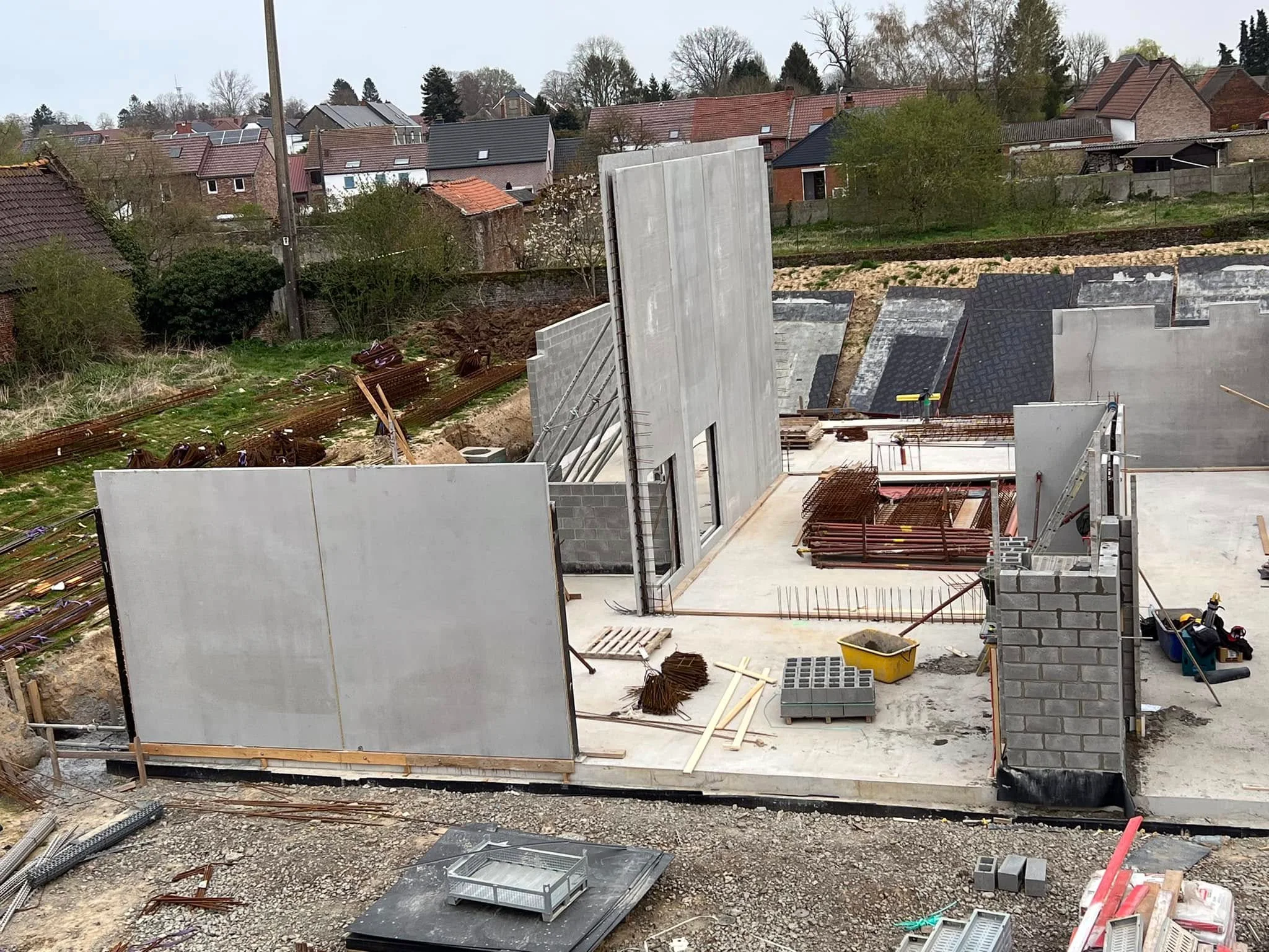 Vue du chantier avec de grands panneaux en béton, des murs en blocs et des matériaux stockés